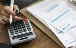 Female Hand Holding Pen Calculating Invoices