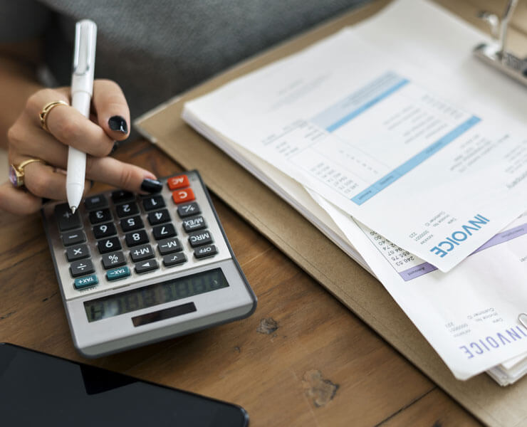 Female Hand Holding Pen Calculating Invoices - Detecting banking fraud in healthcare